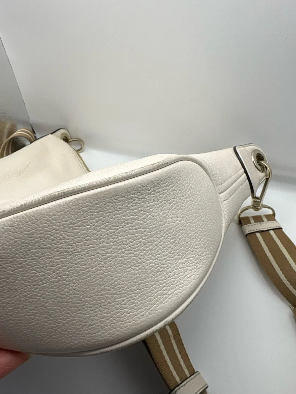 Kate Spade New York cream leather crossbody bag featuring a striped webbing Stra